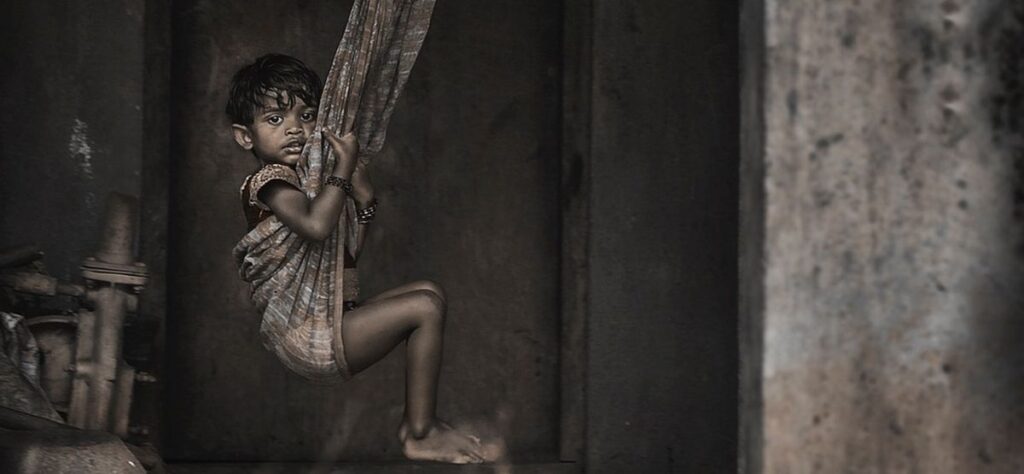 Könnte man hier gute Werke tun -- ein Ausschnitt desselben Bilds wie im Titel, ein Junge, wahrscheinlich aus einer ärmeren Familie. Das Bild ist schwarz - weiss, mehr schwarz als weiss.